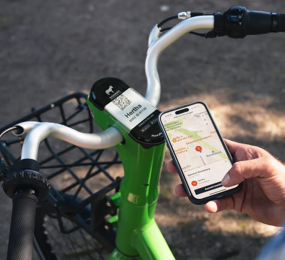 Digitale Mobilität – E-Bike und Smartphone-App in der KielRegion Hand hält Smartphone mit Mobilitäts-App neben einem grünen E-Bike