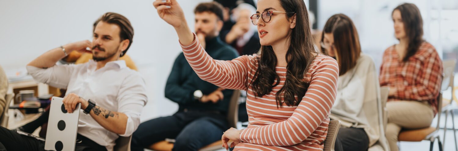 Frau im Klassenzimmer meldet sich