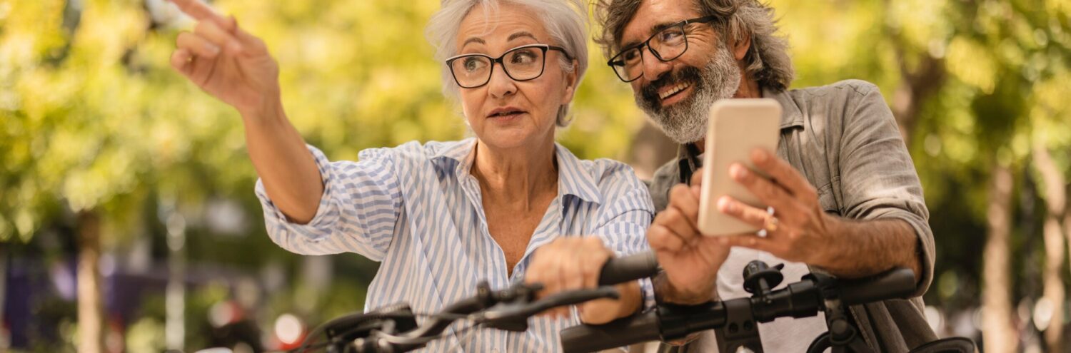 zwei Menschen auf einem Fahrrad und einem Scooter, die nach links zeigen und dahin blicken